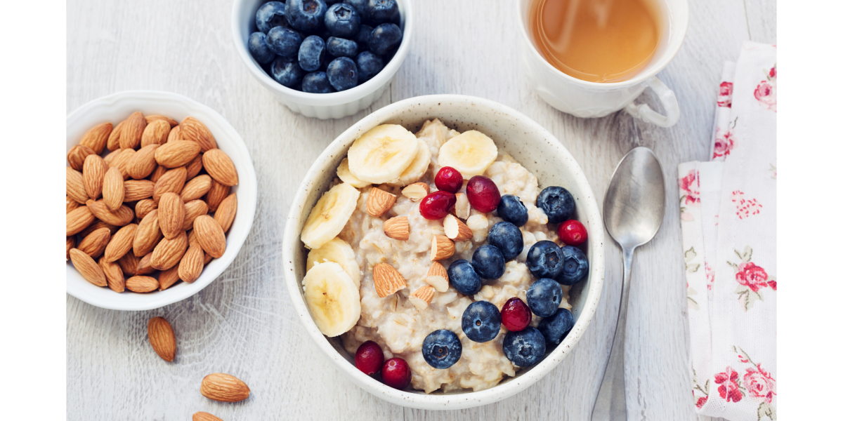 Recipe photo for fruity and creamy no-cook oatmeal. White bowls and light grey background. Almonds and fruit in smaller bowls.