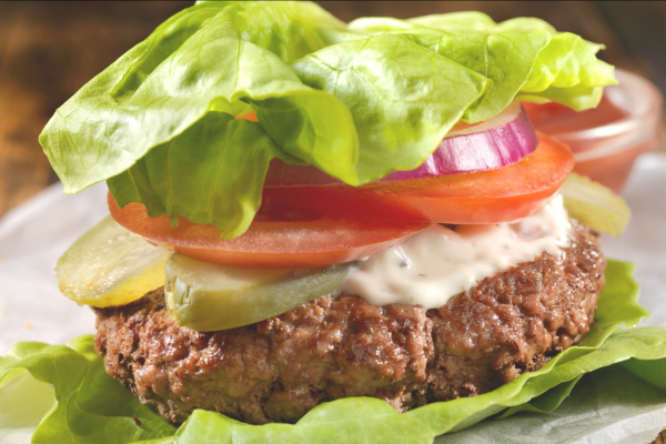A classic California Style Burger, but wrapped in lettuce instead of a bun. Blurred and mostly white background.