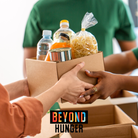 A photograph of a volunteer handing a box of food to someone, with the Beyond Hunger logo at the bottom of the image